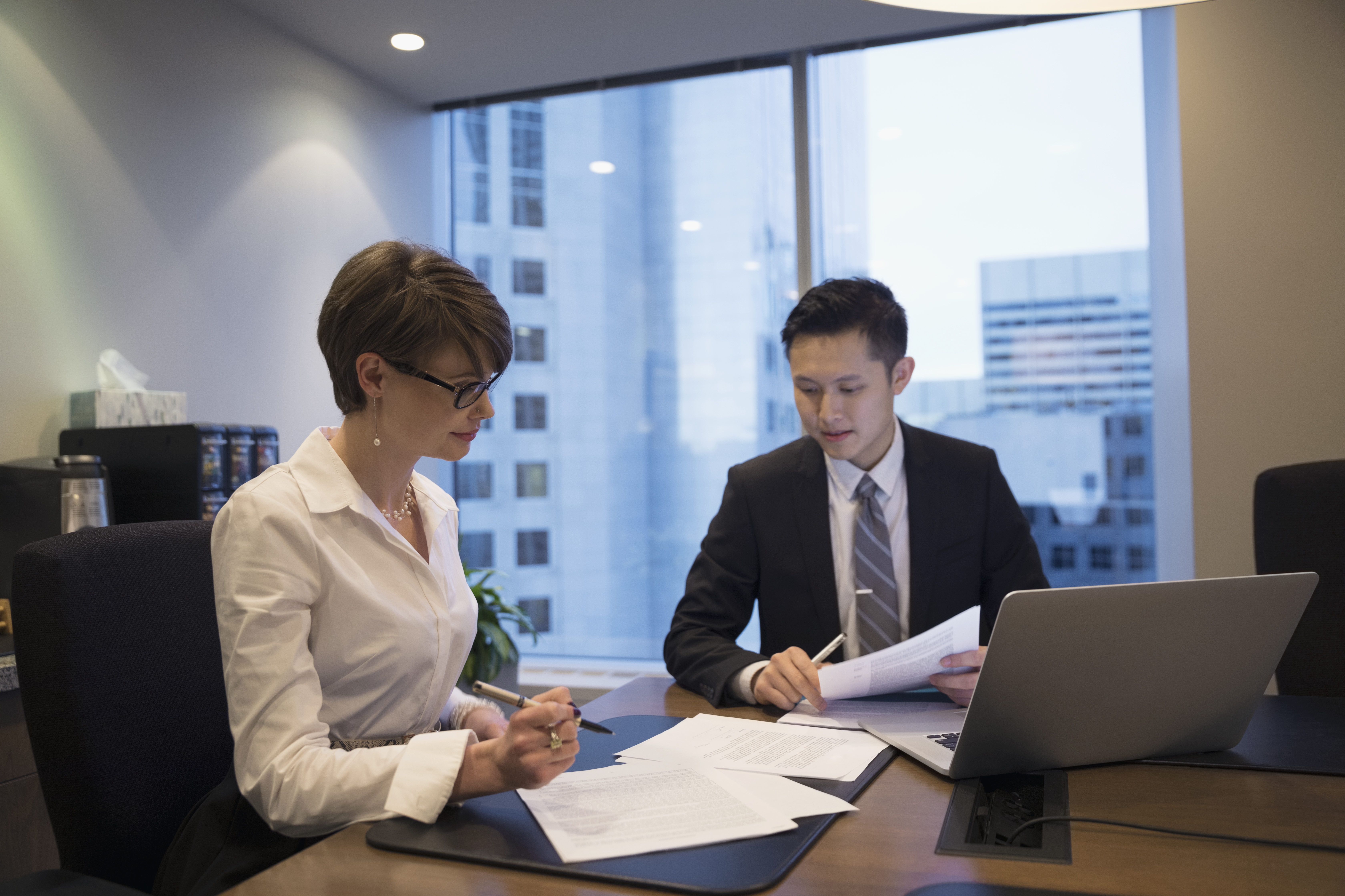 Signing Title Company Documents business colleagues in office discussing paperwork and content on laptop