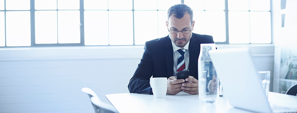 Bizman-using-smartphone-med Businessman using smartphone in office