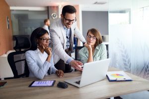 Office workers reviewing financials on laptop