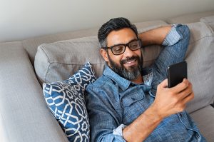 Man relaxing on couch with mobile device