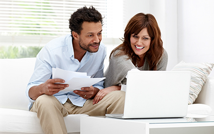 Relaxed couple using laptop for information Couple reviewing finances on laptop