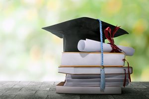 Graduation cap and diploma on table of books