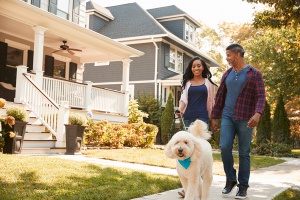 couple walking dog in single family house neighborhood