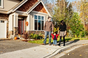 Couple with kid in front of single family house with pumpkins