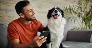 man holding mobile phone with dog