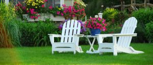 Adirondak chairs on lawn surrounded by spring flowers