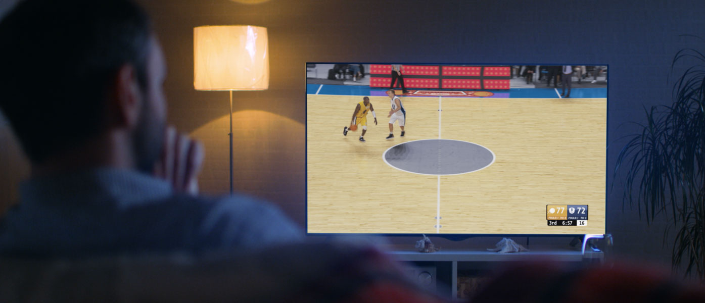 Home Pursuit March Madness with man on couch watching basketball game on tv