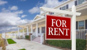For rent sign in front of single family house with blue sky