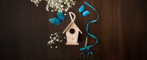 Birdhouse with blue ribbon, baby's breath flowers and blue monarch butterflies on wood background